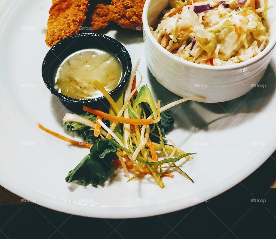 crispy chicken tenders with a honey dill sauce and a fresh coleslaw on the side with a nice garnish