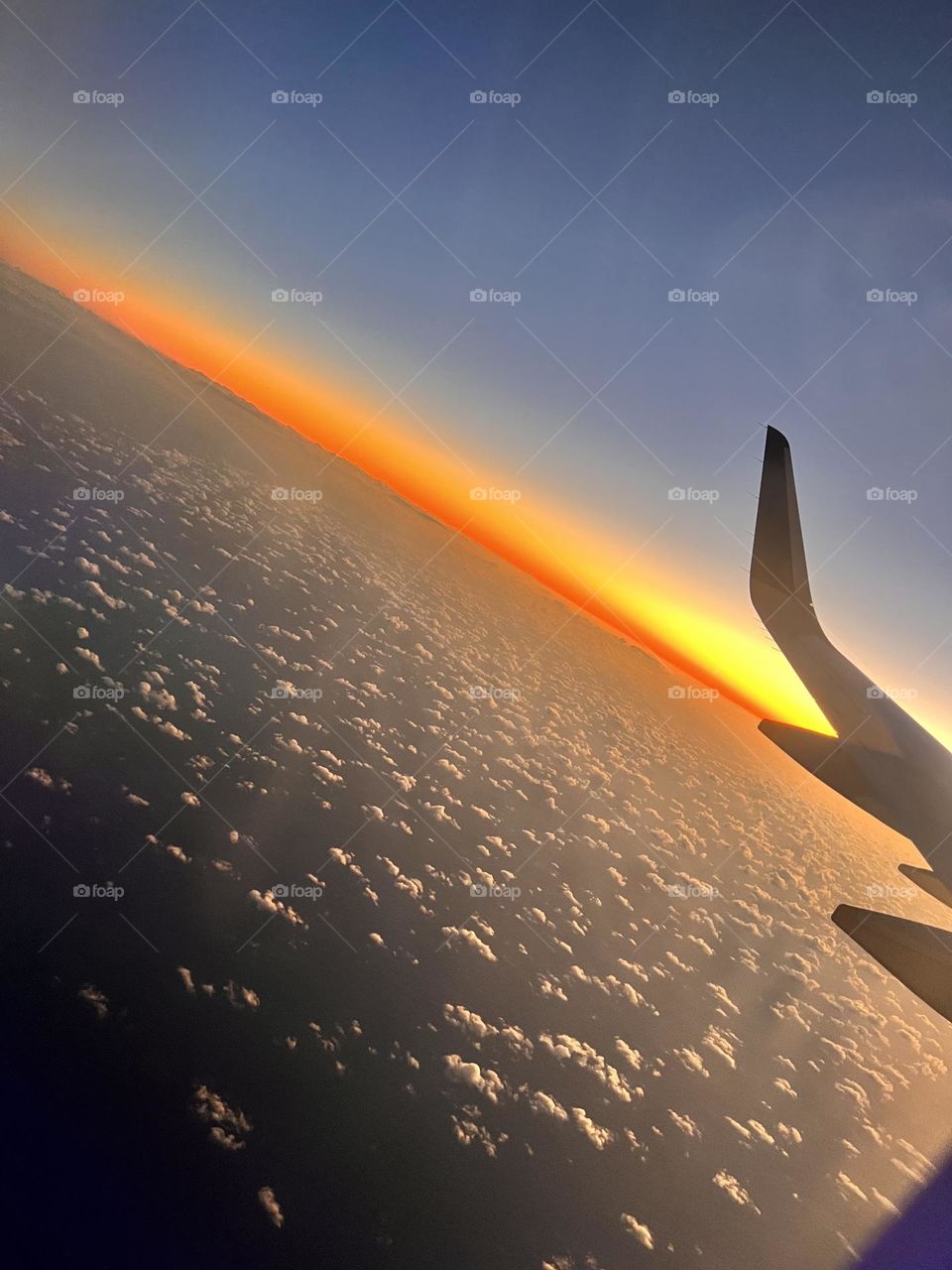 Flying through the sky as the sun sets casting beautiful golden colors upon the horizon down to the earth 