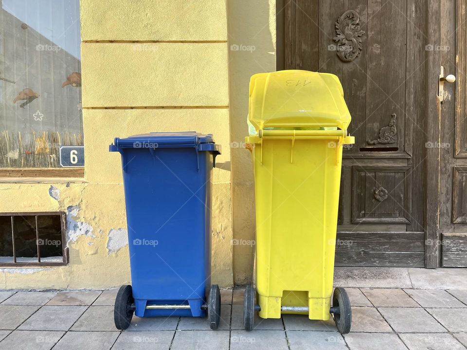 Yellow and blue trash bins near the wall