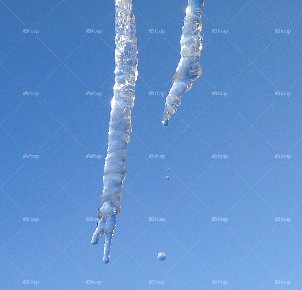 Crisp clear icicles melting in the noonday sun.  Water droplets cascading down.
