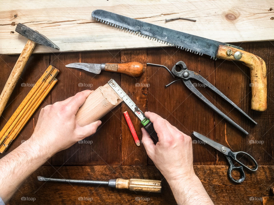 Some things need repair. Hands of man measuring piece of wood using tape measure