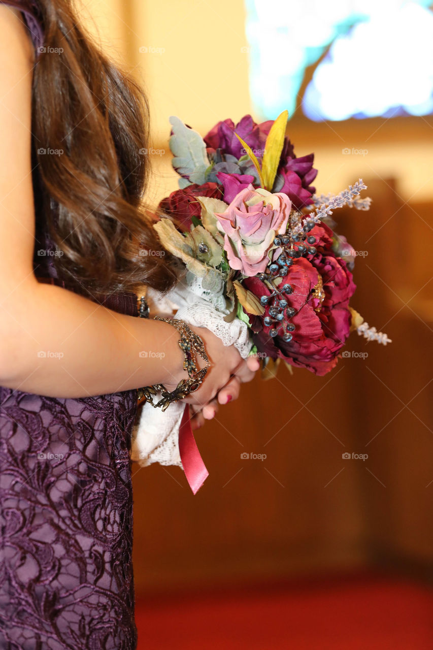 Brunette Bridesmaid in plum or purple holding floral bouquet for wedding ceremony 
