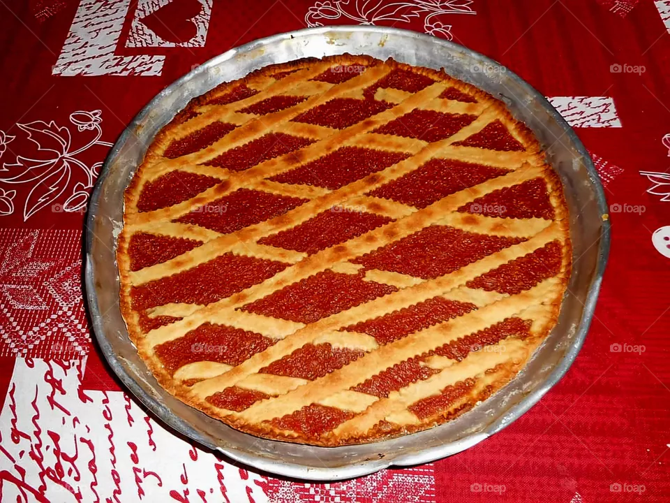 Homemade tart with strawberry jam on a red and white tablecloth