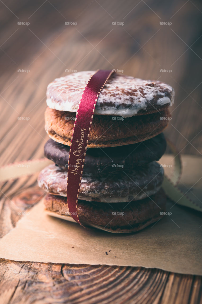 A few gingerbread cookies wrapped in red ribbon Happy Christmas on wooden table. Plain background. Portrait orientation