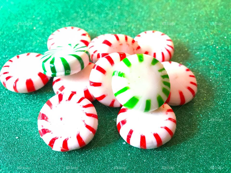 Red and green Peppermint Christmas candy. Green glitter background 