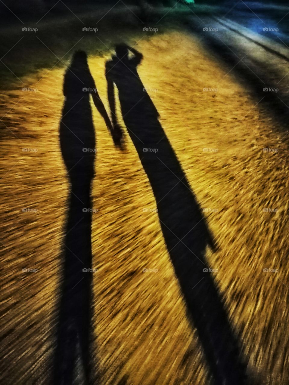 Shadow of a couple holding hands while walking at night.