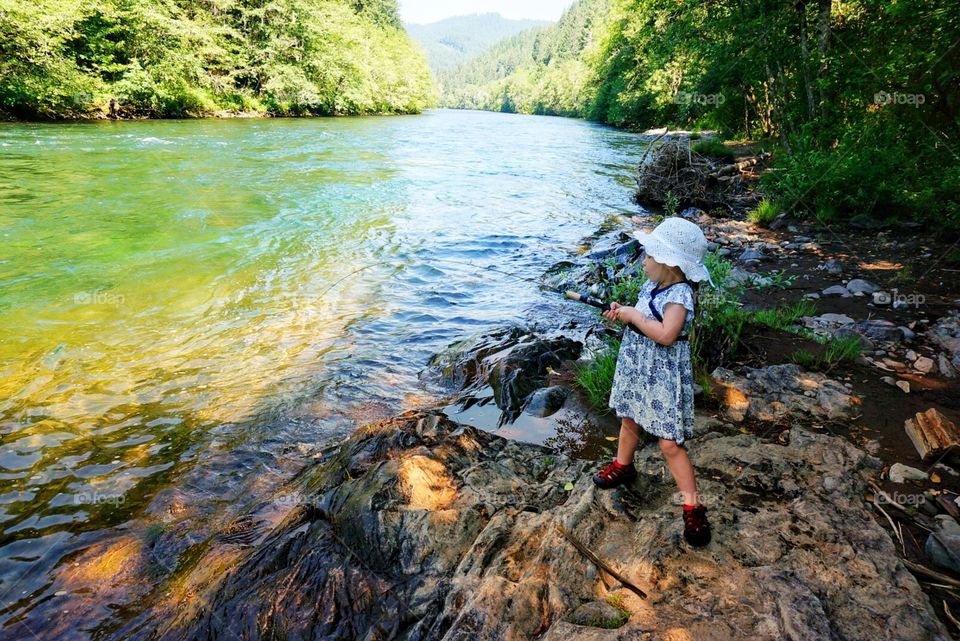 Little girl fishing in a dress along the river