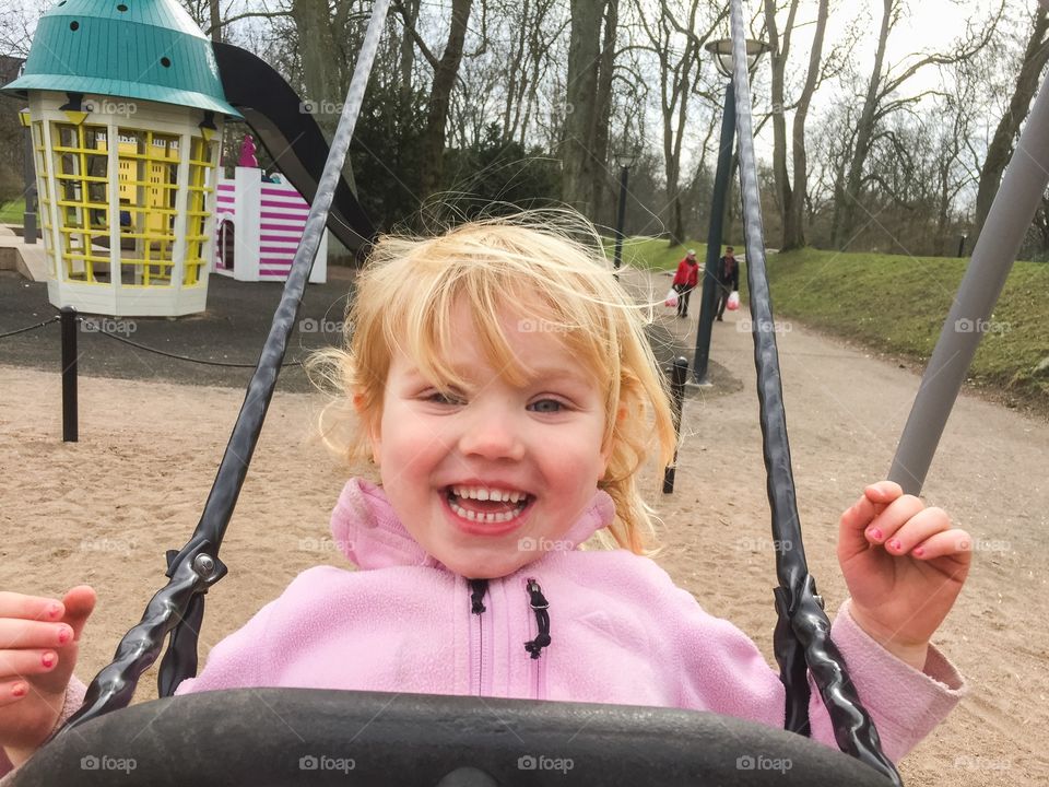 little girl swinging at a playground in stadsparken in Lund Sweden.
