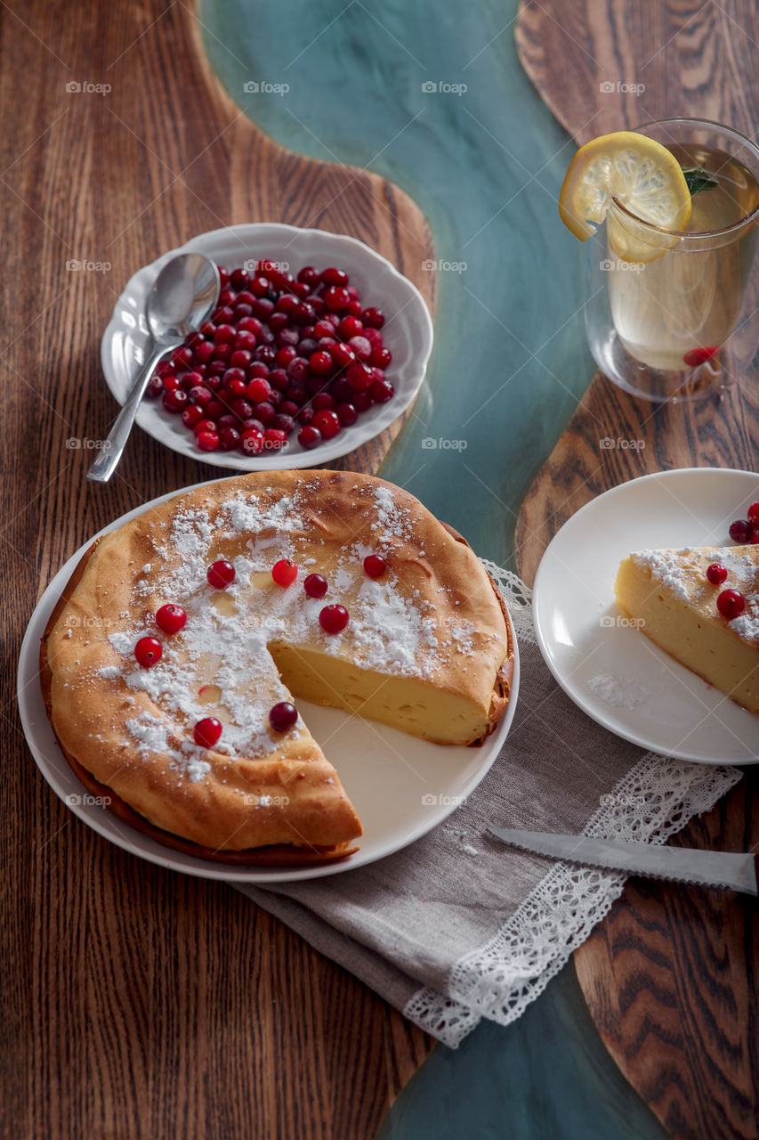 Cheesecake with cranberries and sugar on wooden background