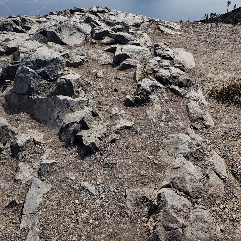 Jagged rocks on the edge of a cliff leading to the water below. 