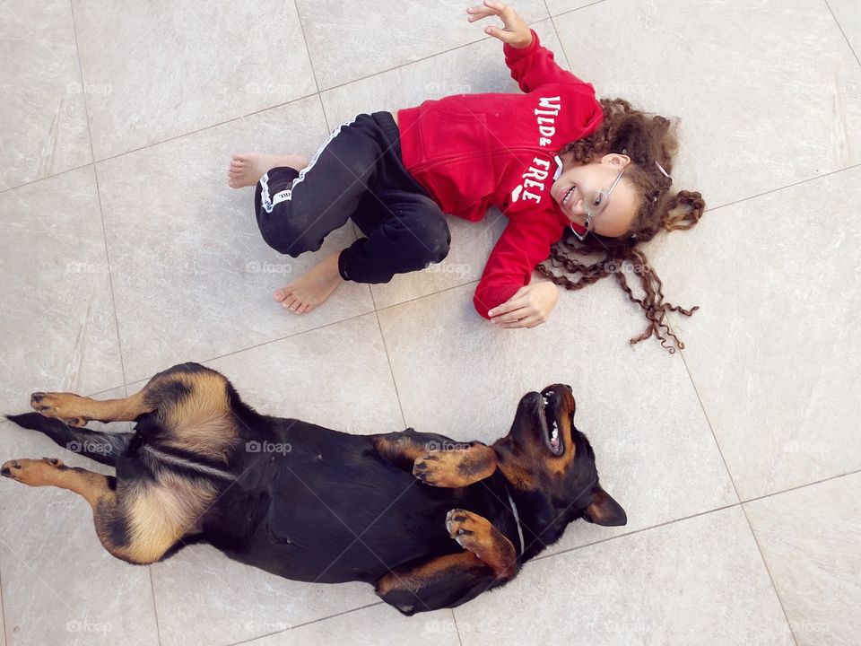 Little girl having fun with her friend Rottweiler