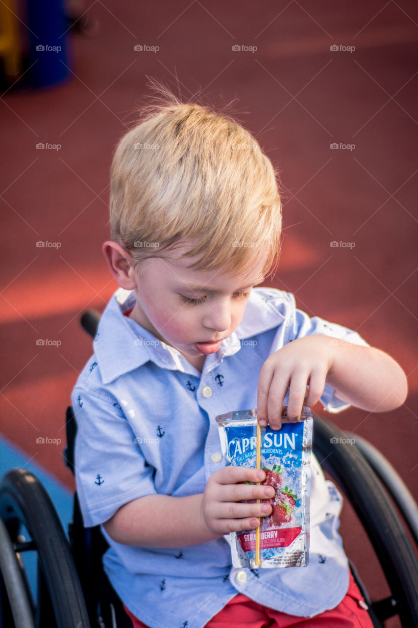 Young Boy in Wheelchair Holding a Capri Sun 