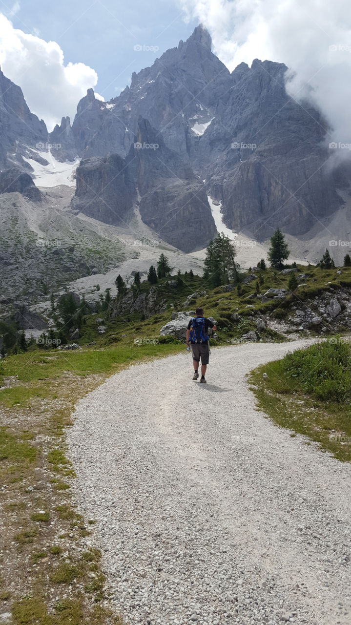 Man hiking in the mountains,  high mountain peaks and clouds 