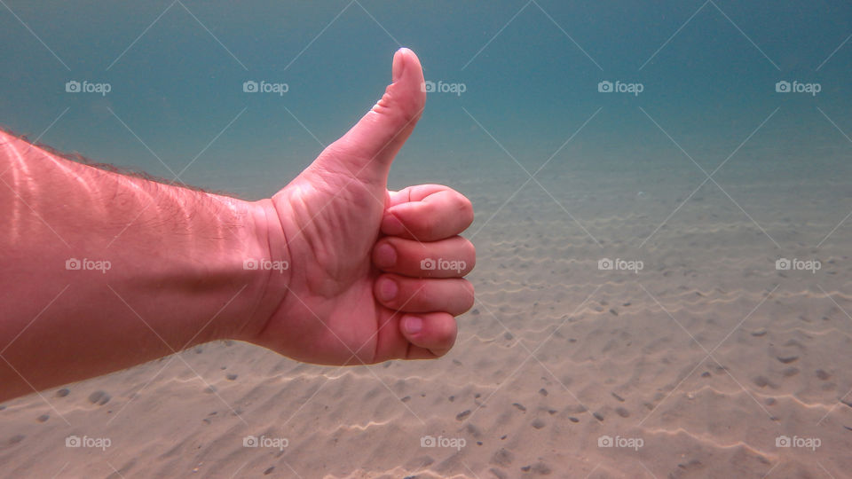 thumbs up underwater in the deep blue sea. man swiming and diving in the ocean