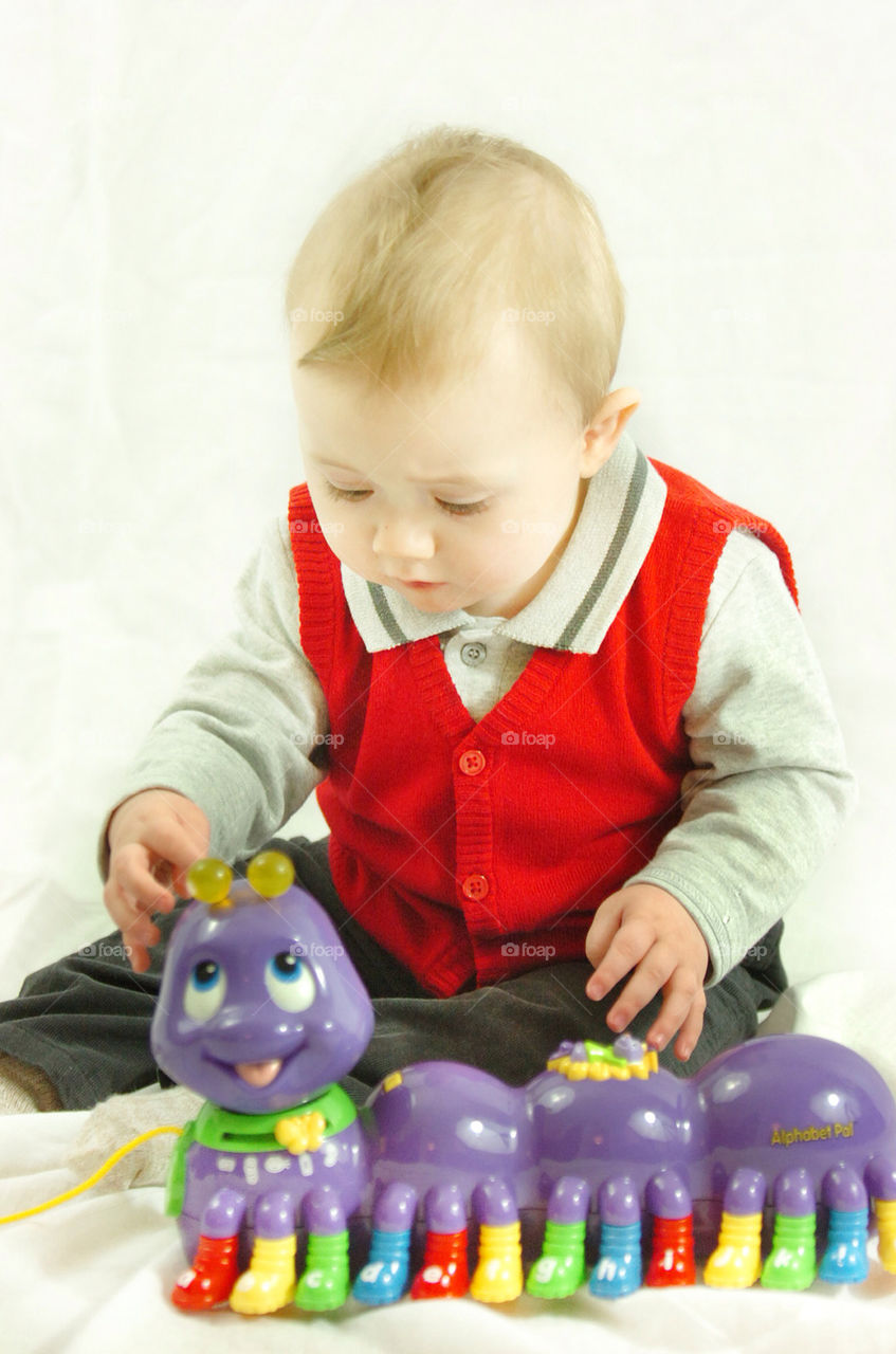 BABY BOY SEATED AND PLAYING WITH A PURPLE SNAKE TOY