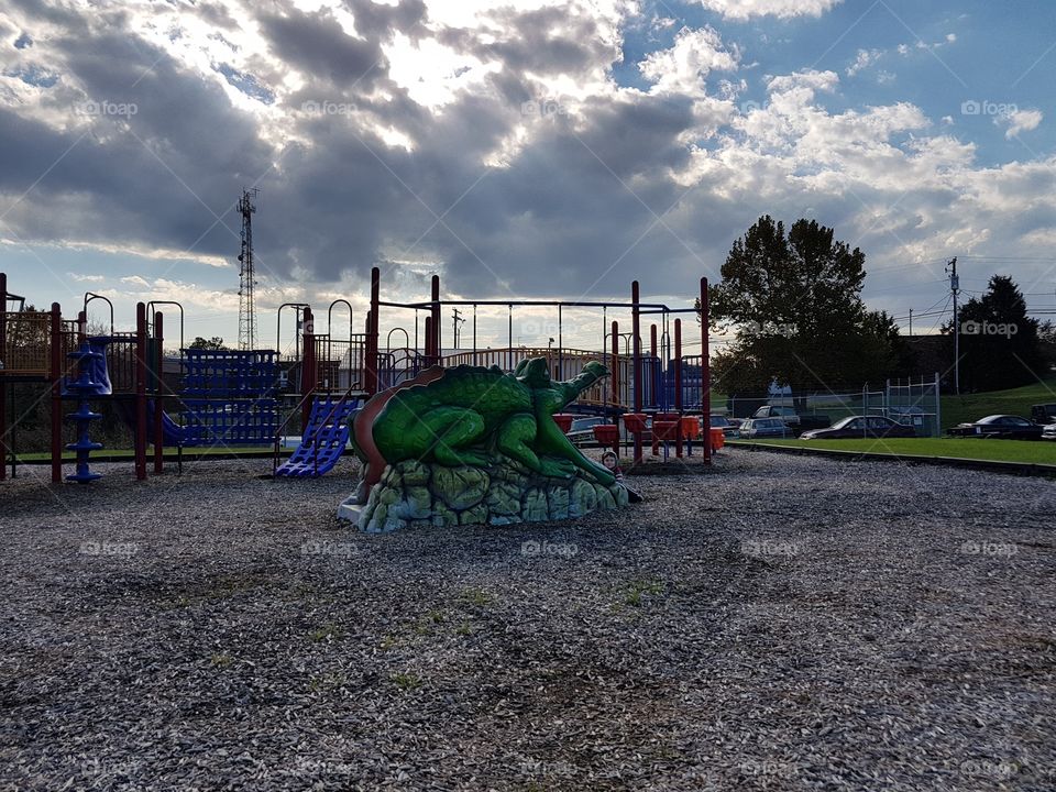 Playground with large alligator slide, big, dark clouds and munched ground