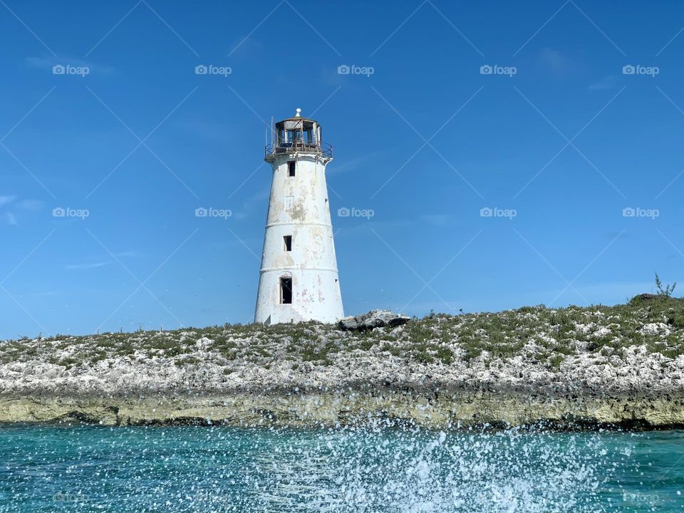 Beautiful Sea foam in front of a lighthouse and blue sky backdrop at Nassau Bahamas. 