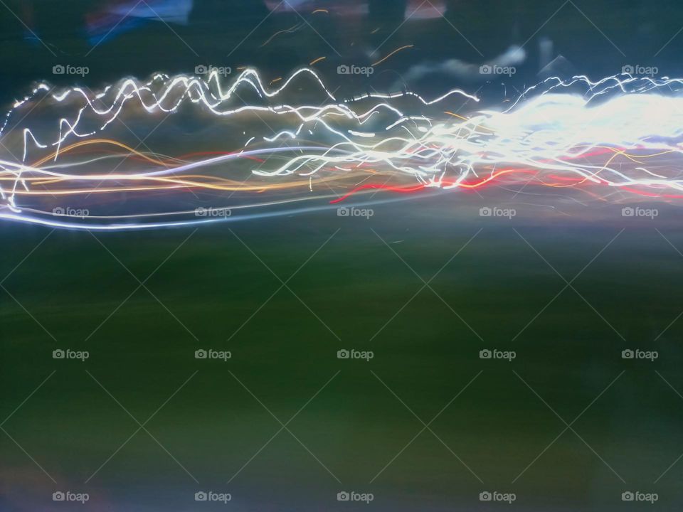 Light painting created through various light sources residents vehicles headlight to brake light street lamp police light. Long exposure in night traffic on road. Blurred lights captured while driving at
night