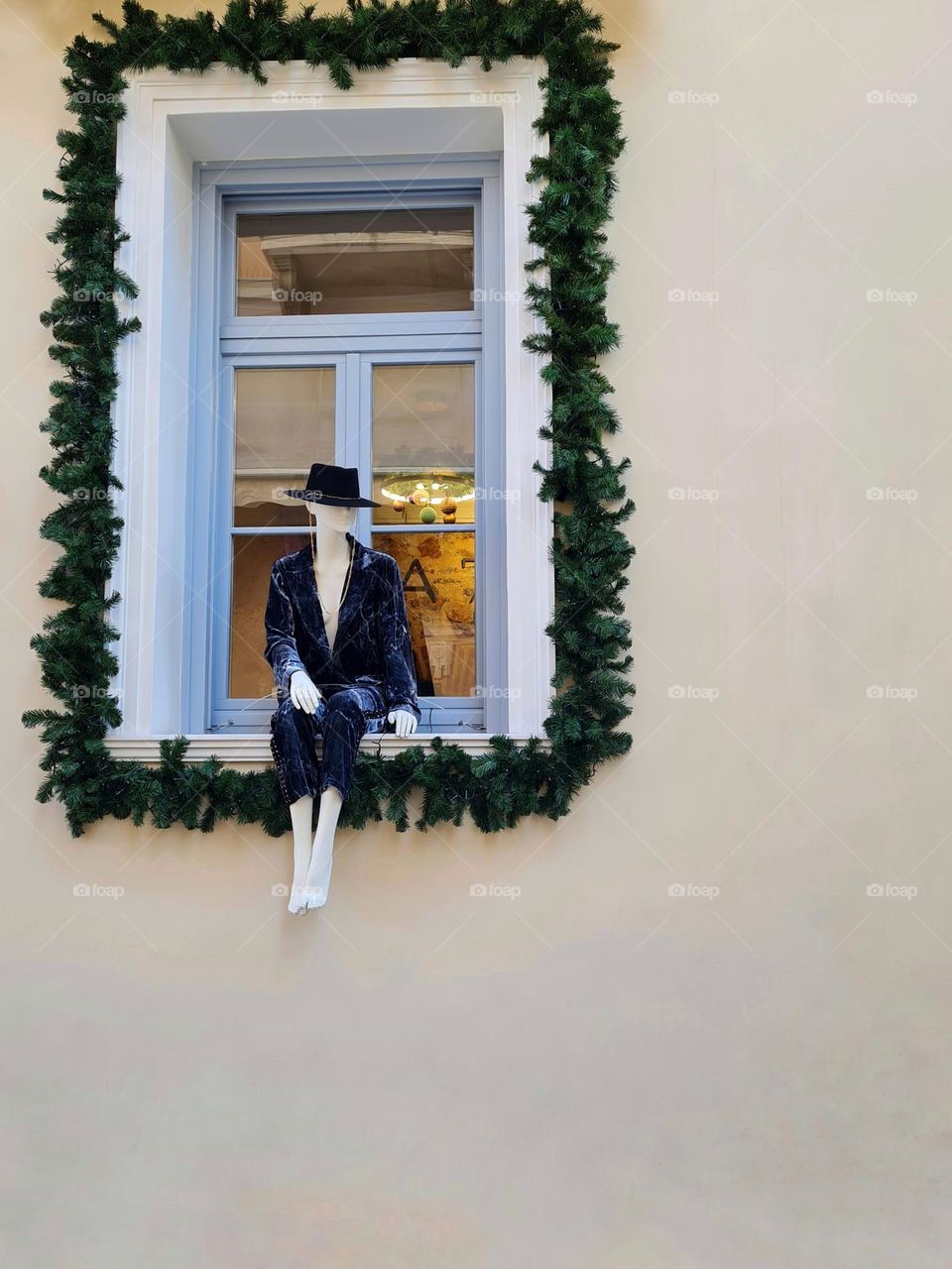 mannequin poses seated on the window of an elegant shop