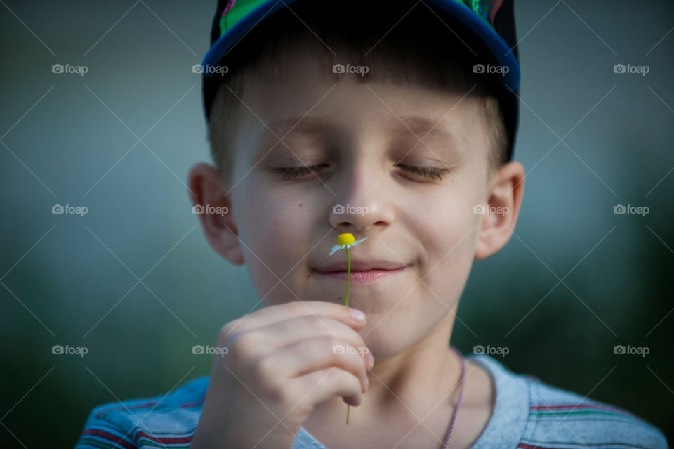 A portrait of a boy with daisy in the hand