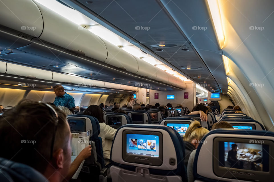 Sydney, Australia - December 10, 2015: Onboard Hawaiian Airlines Flight HA452, bound from Sydney to Honolulu. A flight attendant walks around the cabin before safety preparation procedure. Such procedure is common to all flights prior to take-off.