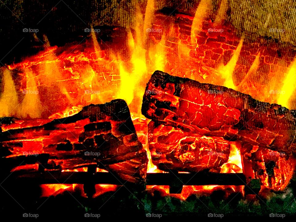 Fiery fireplace with bright red and black color  firewood and yellow flames