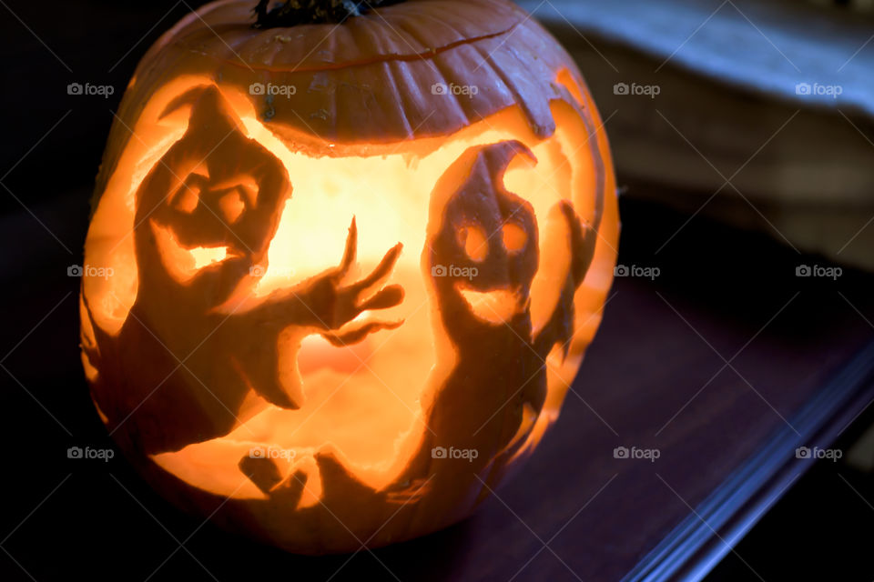 Halloween pumpkin indoors with two ghost friends or friendly ghosts waving hello 