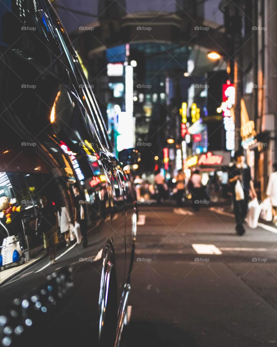 Neon lights reflect off a vintage car in Tokyo Japan