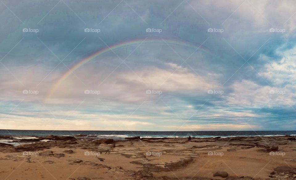 A rainbow shines over a beach in Australia