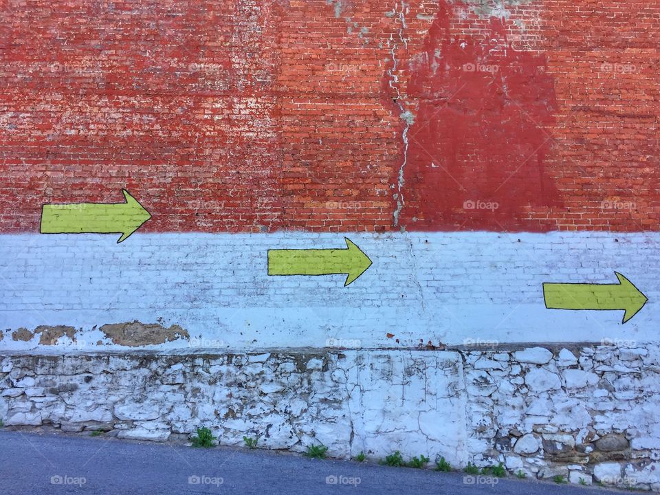 Yellow arrows painted on an old brick wall