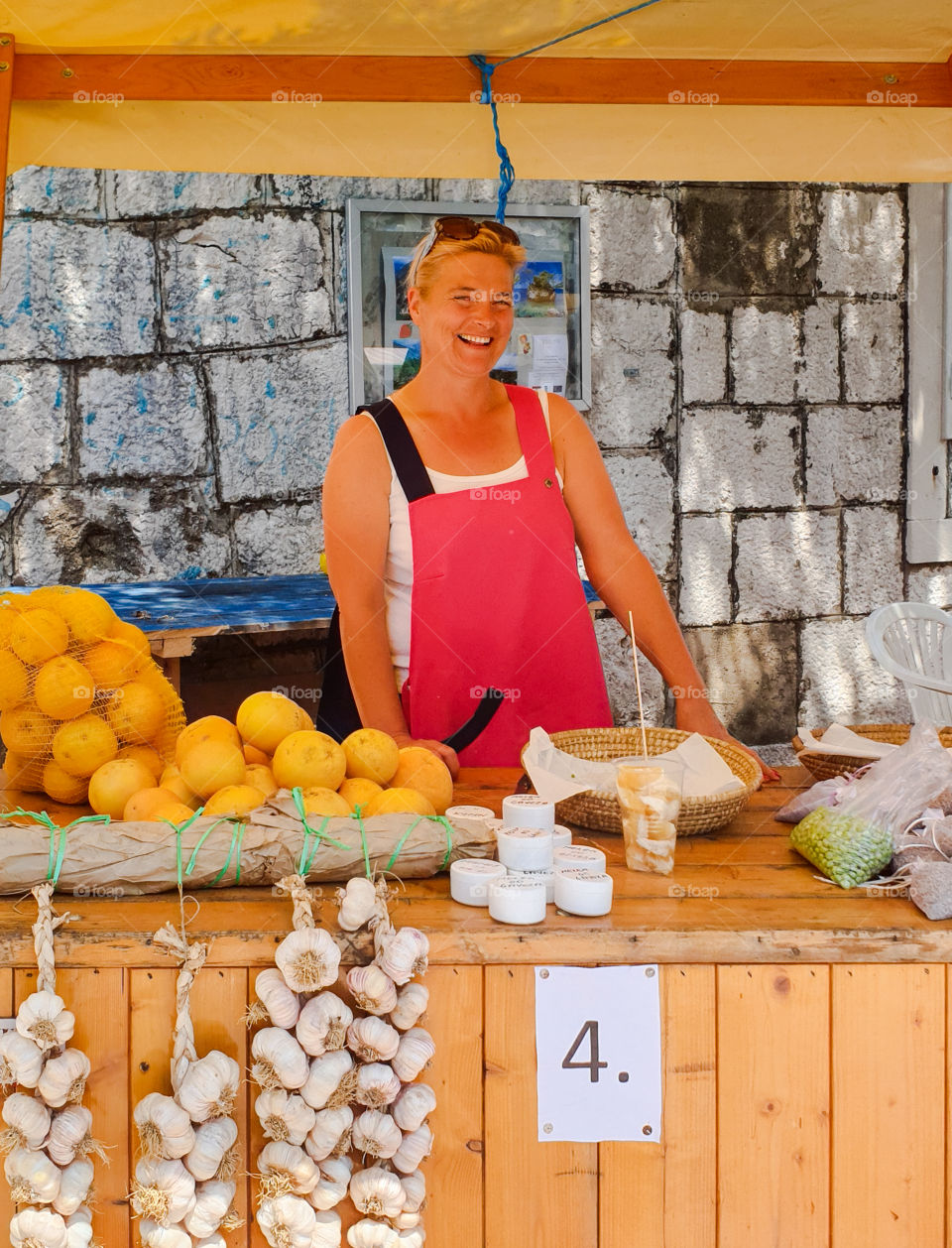 Croatia, Dalmatia.Fair, Beautiful smiling woman stands behind the counter and sells seasonal fruits and vegetables. Summer market