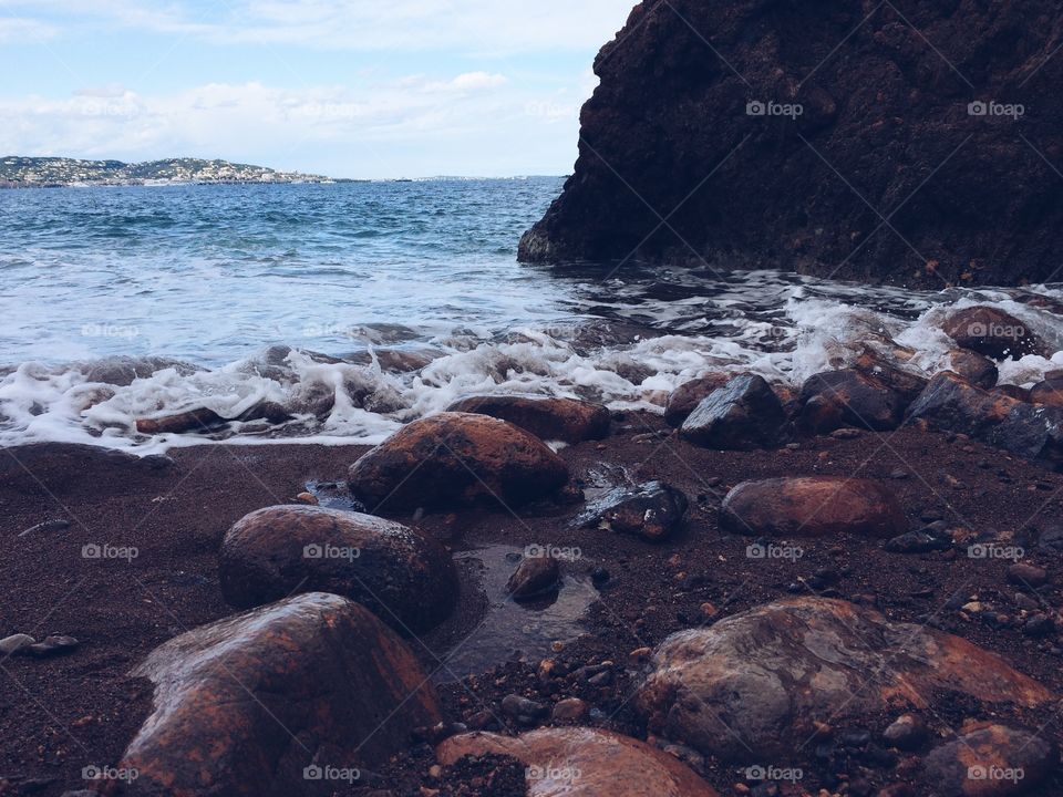 Ocean water flowing over rocks. Waves lightly crashing on a peaceful Mediterranean beach in the south of France