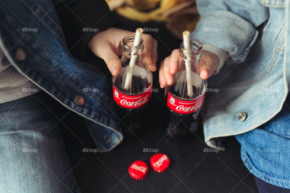 beautiful, stylish, fair-haired children, drinking Coca Cola, eating potatoes, dressed in denim clothes, free photo style. boy and girl have fun, rejoice, beautiful advertisement for coca cola drink