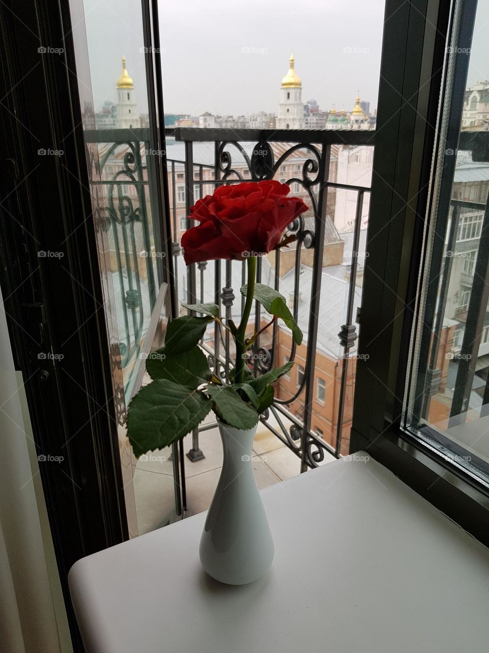 Red rose in a white vase in front of balcony with view on the St. Sophia Cathedral