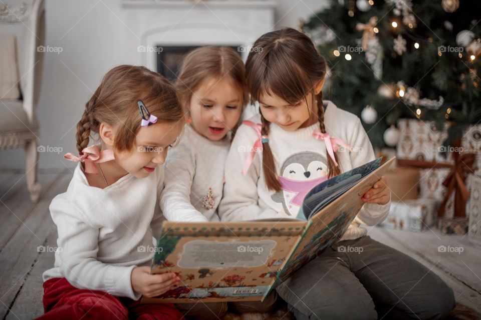 Little sisters near Christmas tree at home