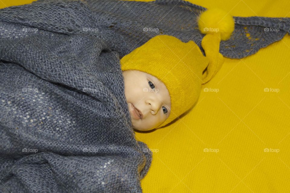 A newborn baby on a yellow and gray background. A photo shoot in the style of Newborn and lifestyle.