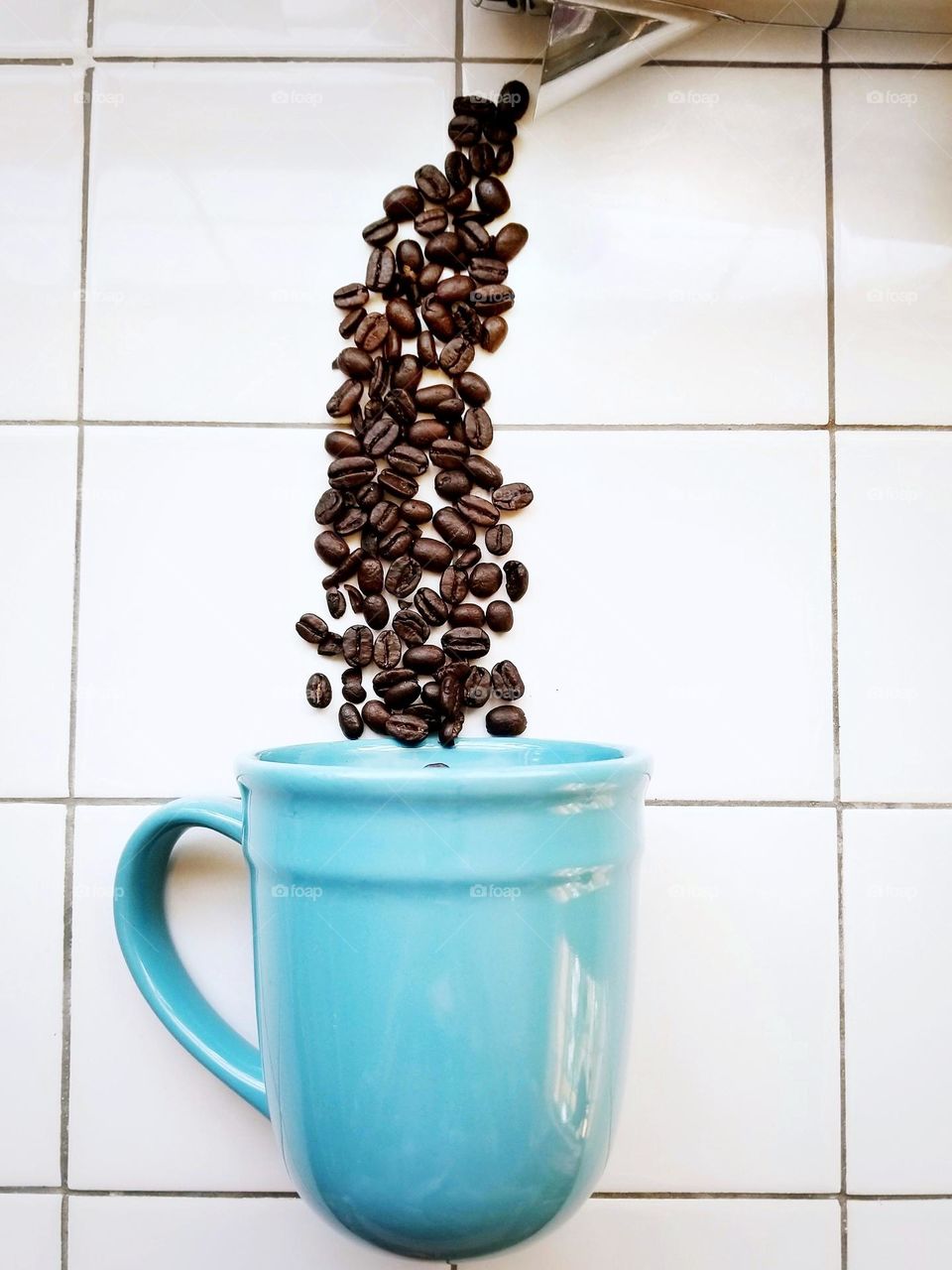 Coffee Beans Being Poured into a Blue Mug from above