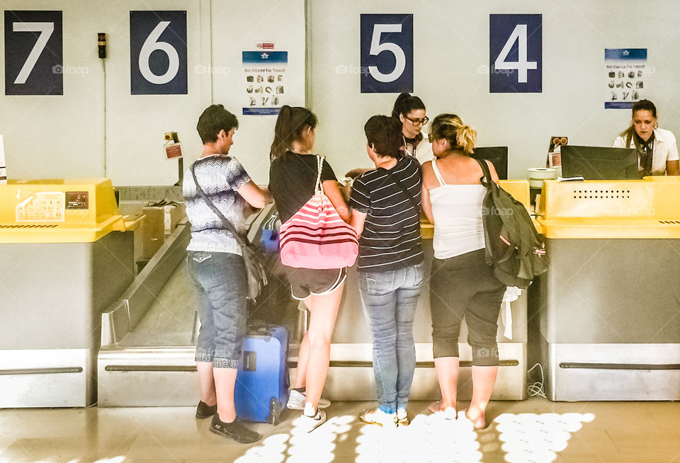 Four Women Friends Passengers Doing Check In At The Airport
