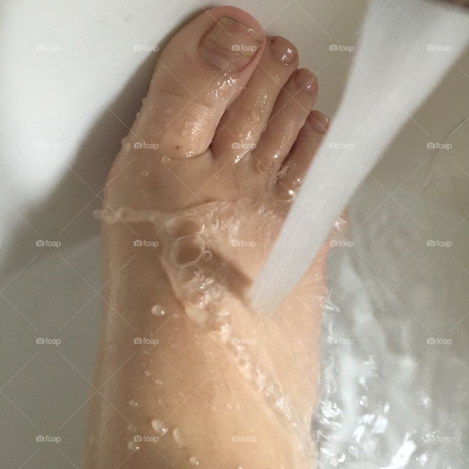 This is a picture of water being poured onto my foot. I had just rubbed lotion onto my foot so my skin is shiny and the water is splashing off. I'm a young white girl.