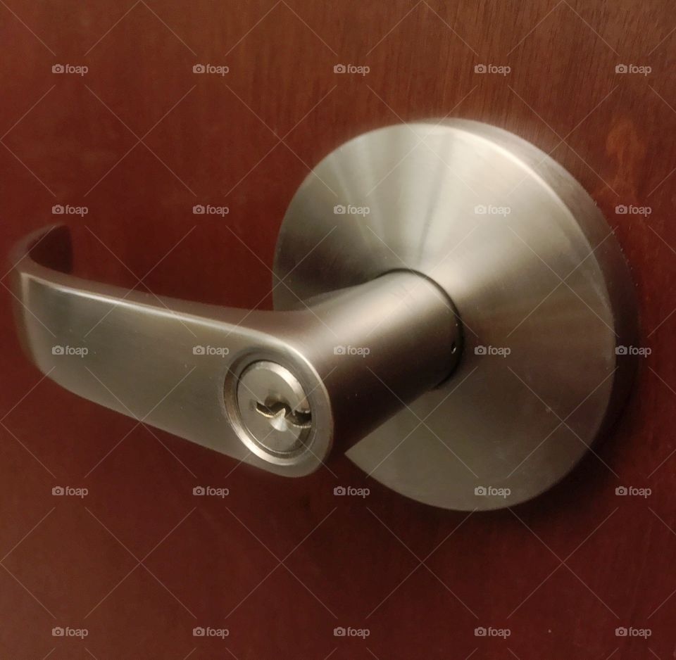 A lock on a silver door handle on a wooden door. 
