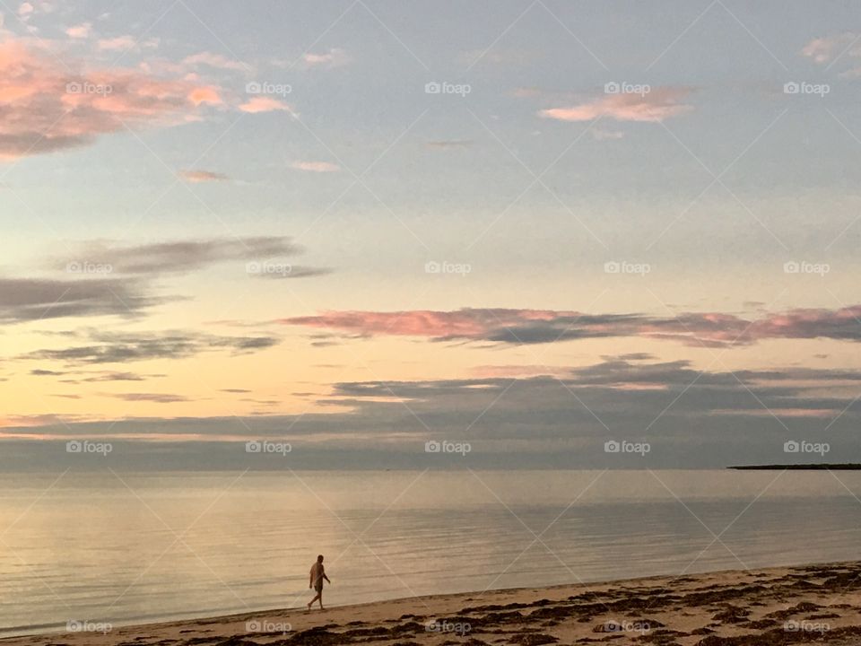 Person wading in water along beach shoreline at sunrise in south Australia 