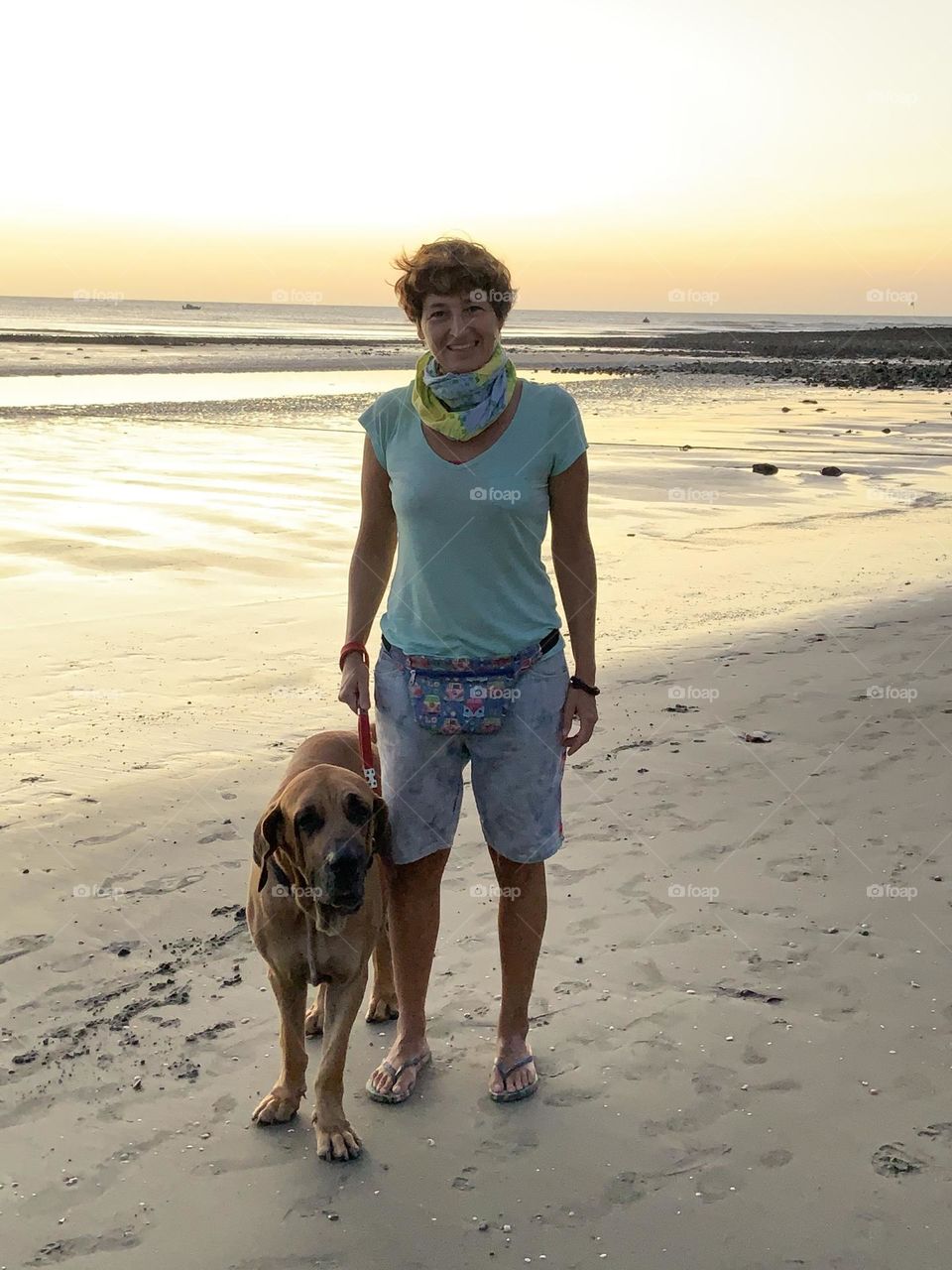 Woman with beach outfit walking with dog 