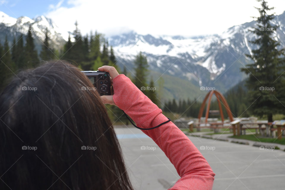 Asian woman (back view) taking photo of Canada's Rocky Mountains in winter, snow, mountains, outdoors