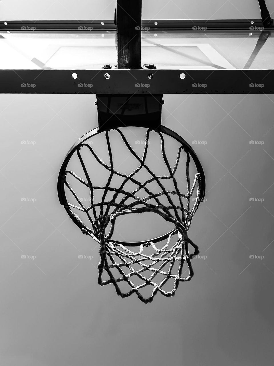 Looking up at a Basketball net on a beautiful sunny afternoon waiting for those slam dunks during game play , in black and white 