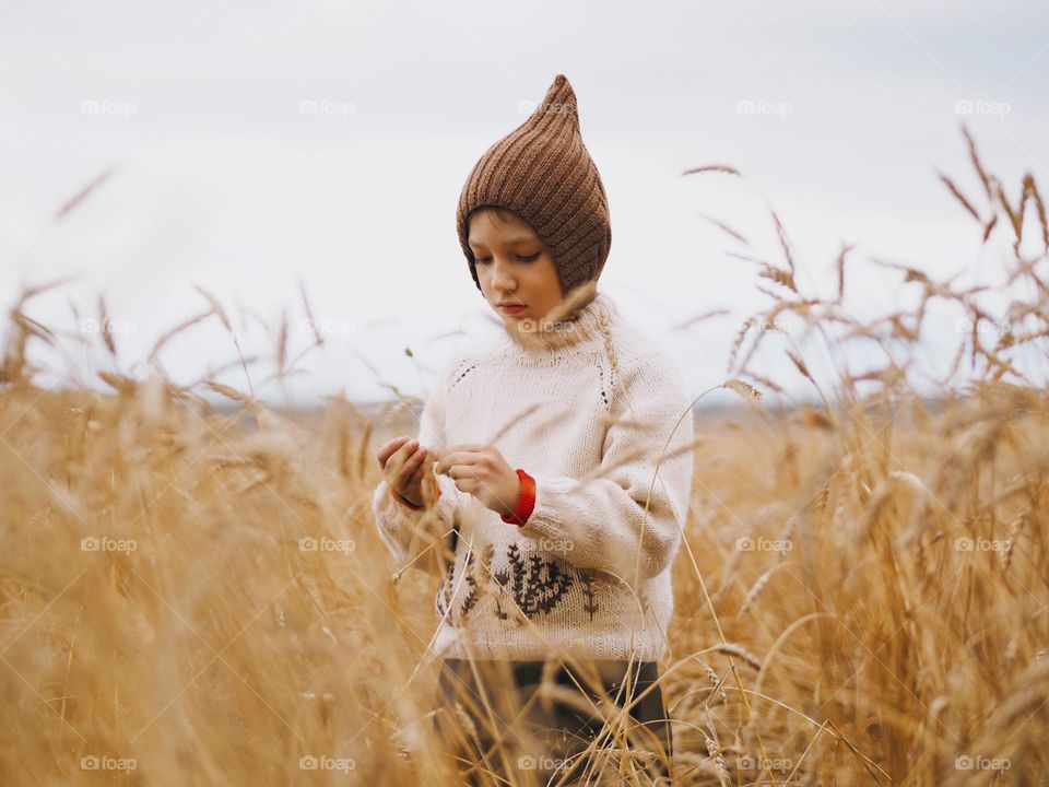 Cute little boy standing in the wheat field on the autumn day, portrait of child 