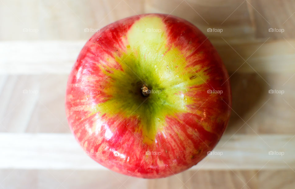 Elevated view of one beautiful  crisp fresh red apple with green and yellow colors isolated on wood table healthy choices art photography background 