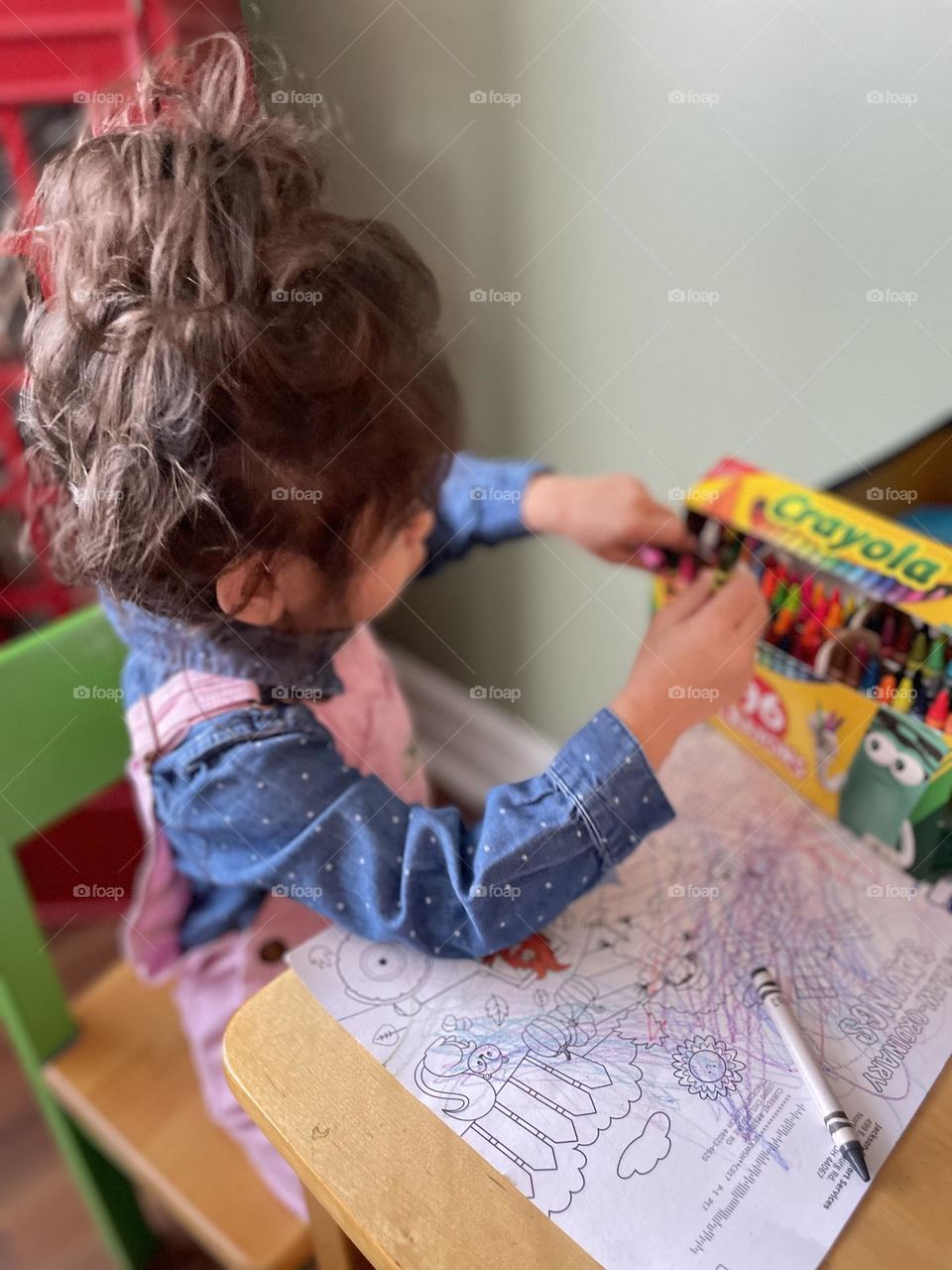 Child selects a crayon to color with out of Crayola pack of crayons, creating with crayons, getting creative with toddlers, children getting creative, making colorful creations with kids, toddler girl loves to color