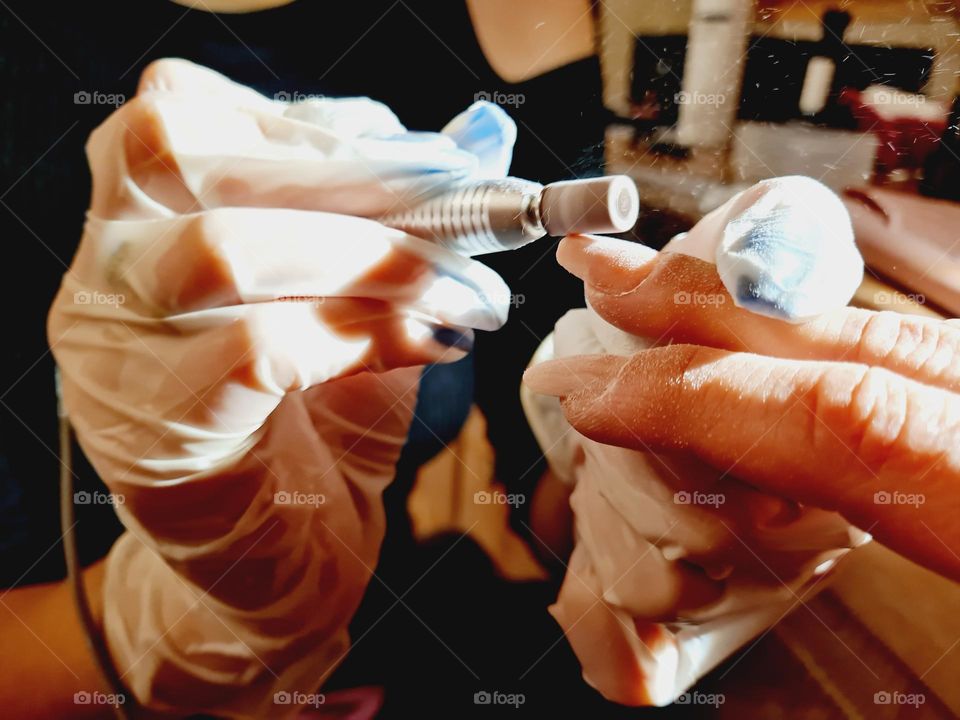 beautician hands detail while performing a nail reconstruction with acrylgel technique