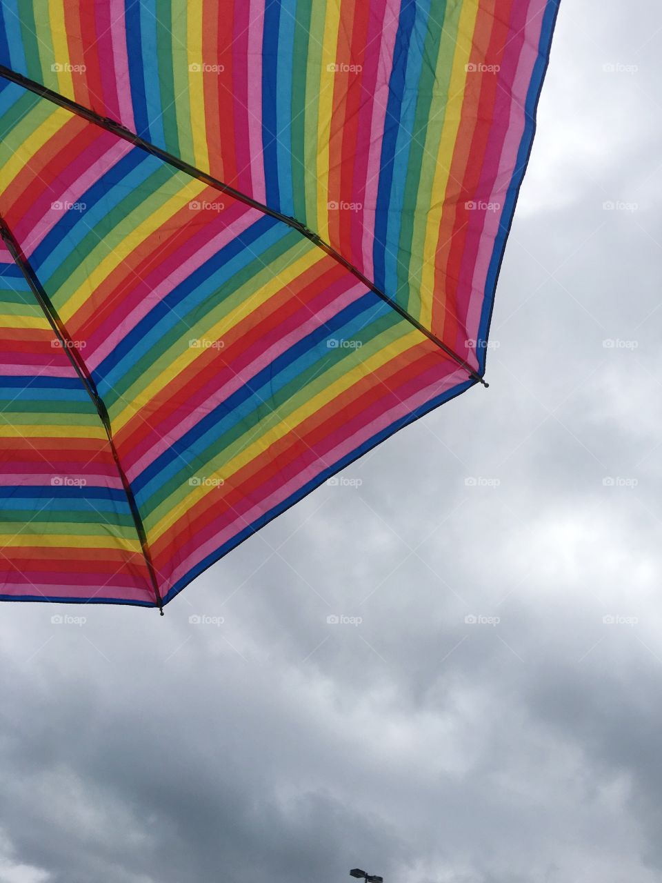 Rainbow umbrella against cloudy sky