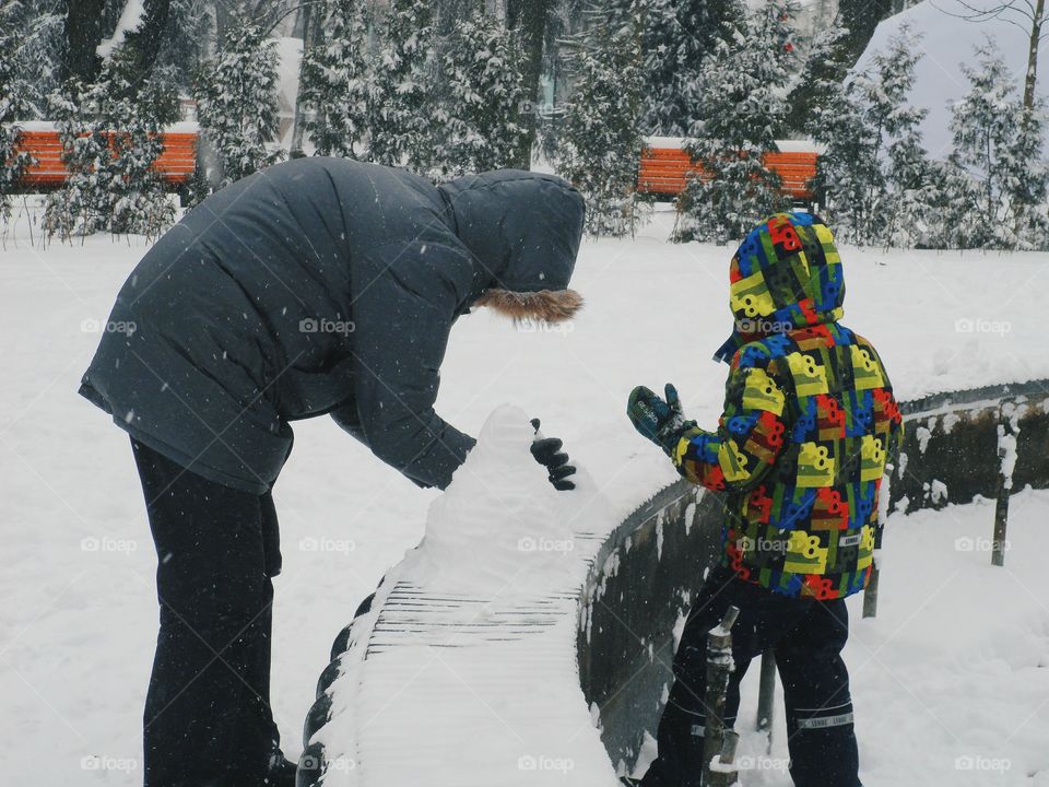 man and child sculpt a snowman in the park, Kiev, winter